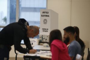 Eleitor e mesários em seção eleitoral brasileira